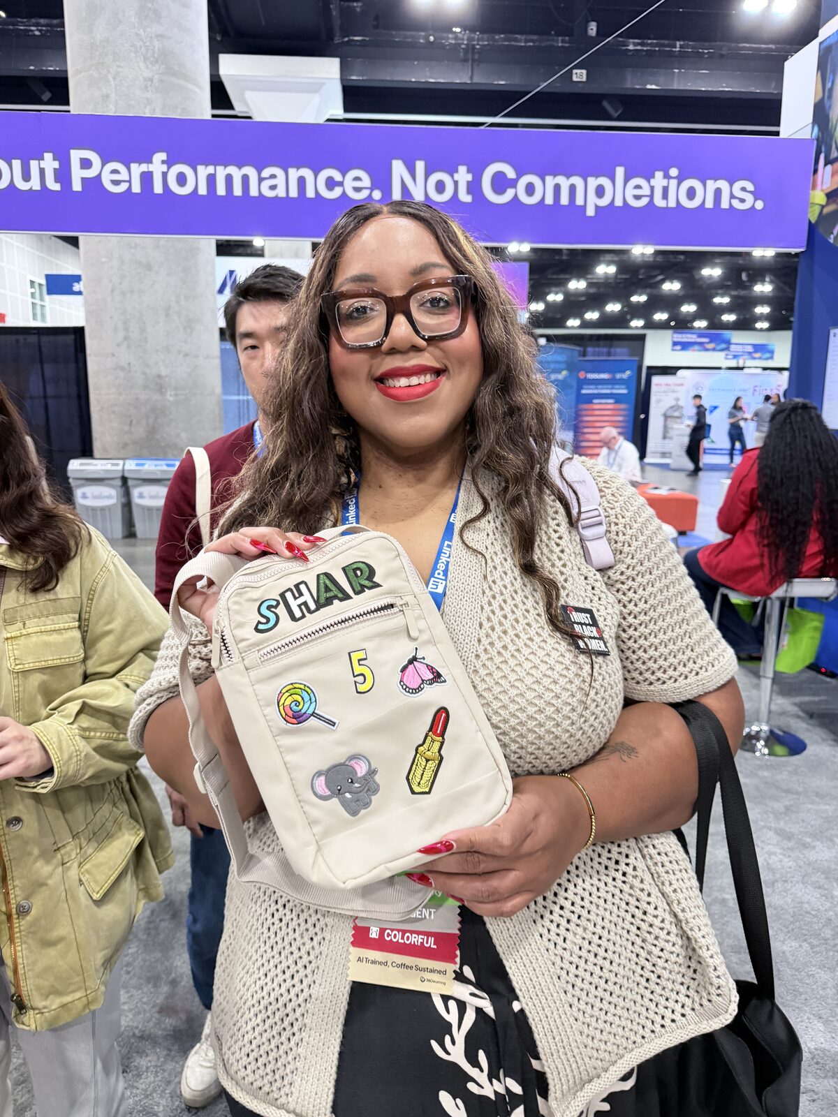 Smiling attendee showing a crossbody bag customized with chenille letters spelling Shar, a number five, and retro patches