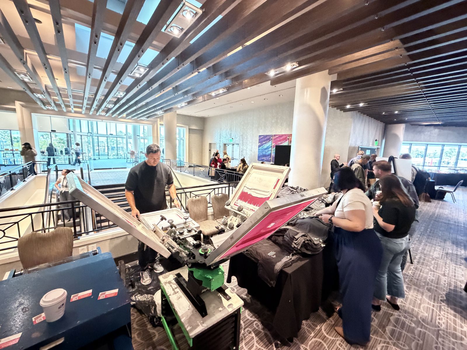 Merch Troop operator working a station on a hotel mezzanine as attendees gather