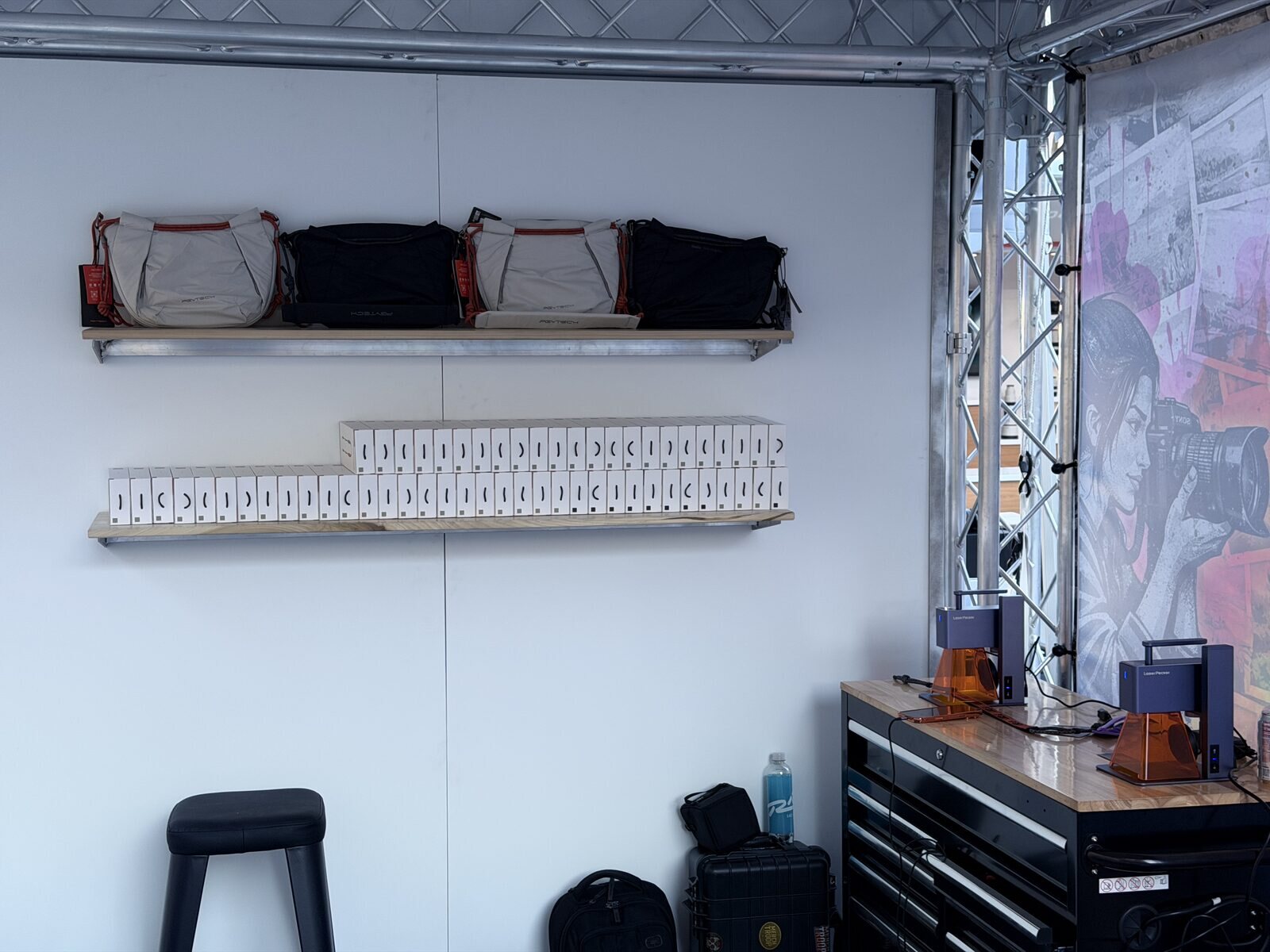 Event station back wall with shelves of blank bags and boxed product staged for customization